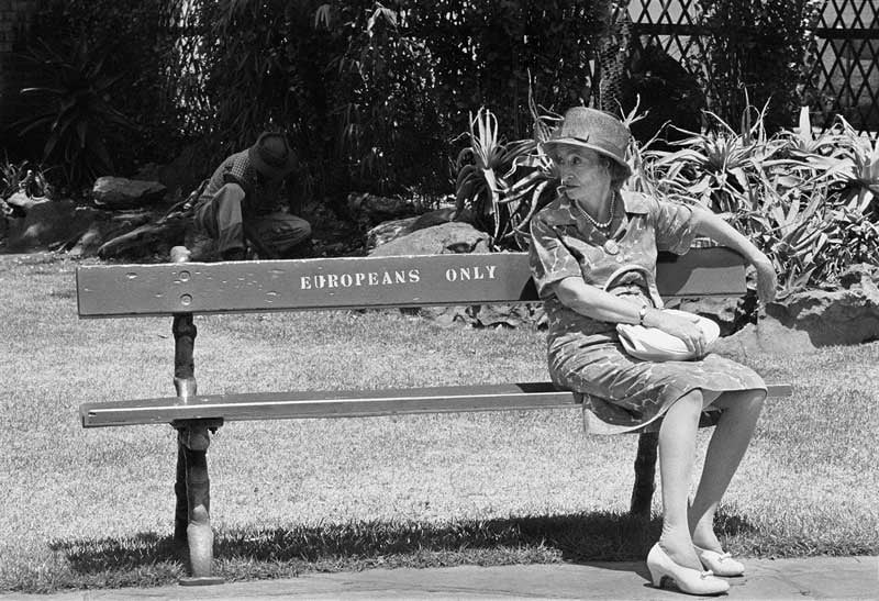 Woman sitting on bench that reads 'Europeans only' in South Africa, 1960s - Photo by Ernest Cole