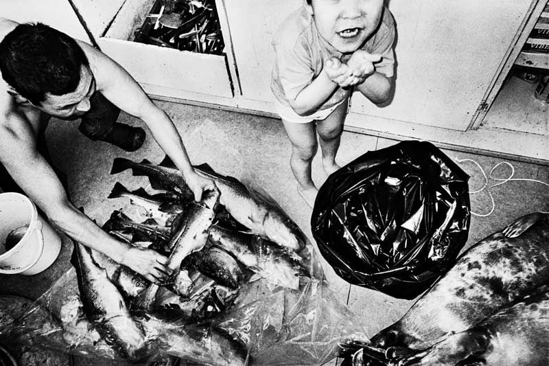 A man and child examine a bag of freshly caught fish, Jacob Aue Sobol