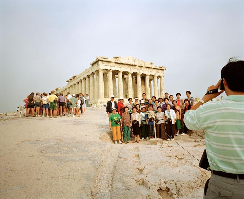 Man takes a photo of a tour group at the Acropolis, Greece. Photo by Martin Parr, 1991