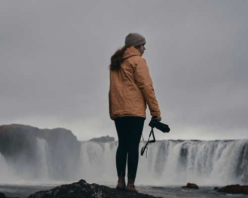 Person holding camera with waterfall backdrop