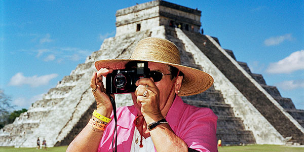 Man wearing sunhat and pink shirt holds a camera on a Mexican holiday